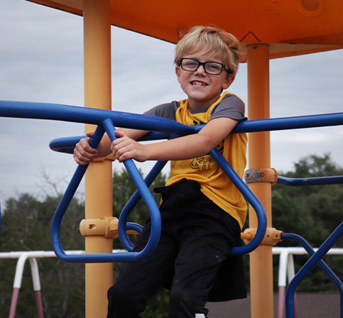 Young male student playing on playground equipment