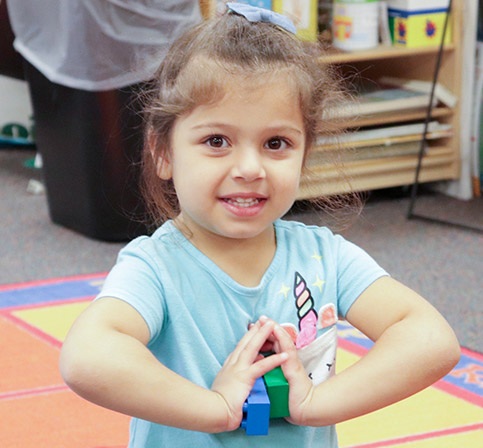 Young female student wearing blue shirt plays with blocks